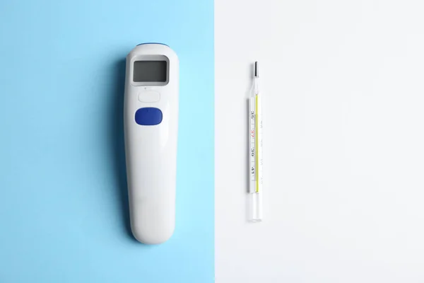 Non-contact infrared and mercury thermometers on color background, flat lay
