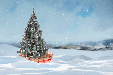 Güzel süslü Noel ağacı ve kış günü karlı ormanda hediyeler. 