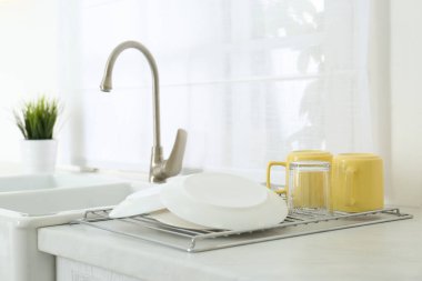 Modern mutfakta temiz bulaşıklar rafta kuruyor.