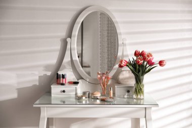 Makyaj malzemeleri, aksesuarlar ve lalelerle dolu şık masası. İç öge