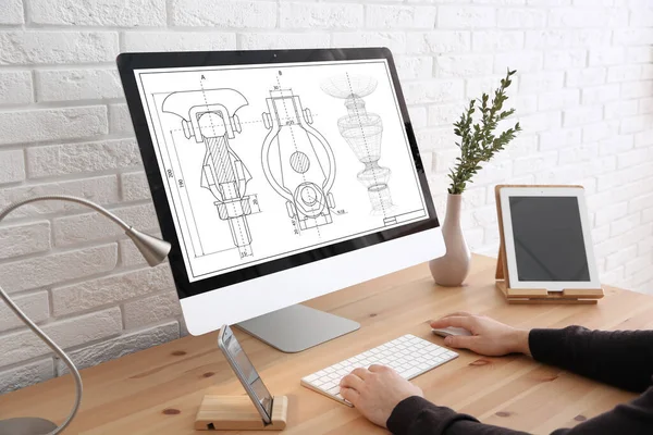Male engineer working with technical drawing on computer indoors, closeup