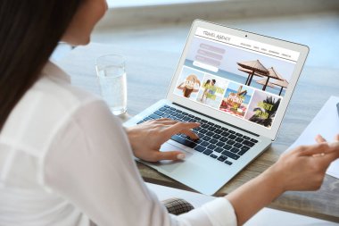 Geziyi planlamak için dizüstü bilgisayar kullanan bir kadın, yakın plan. Seyahat acentesi web sitesi