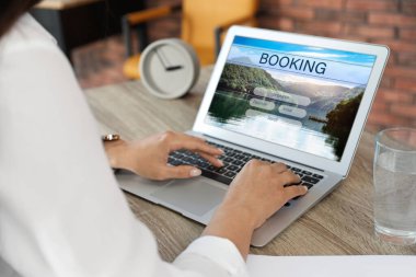 Geziyi planlamak için dizüstü bilgisayar kullanan bir kadın, yakın plan. Seyahat acentesi web sitesi