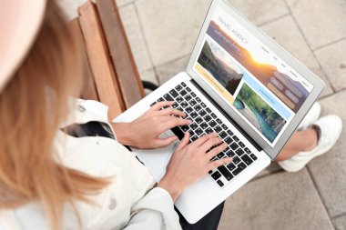 Geziyi planlamak için dizüstü bilgisayar kullanan bir kadın. Seyahat acentesi web sitesi