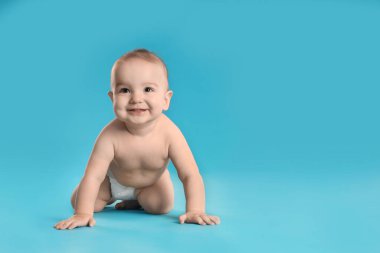 Açık mavi arka planda bebek bezi takmış şirin bir bebek. Metin için boşluk
