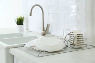 Modern mutfakta temiz bulaşıklar rafta kuruyor.