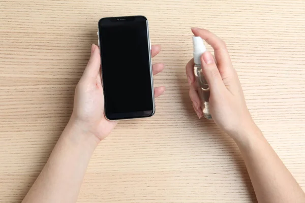 Mujer Rociando Antiséptico Teléfono Inteligente Mesa Madera Vista Superior —  Fotos de Stock