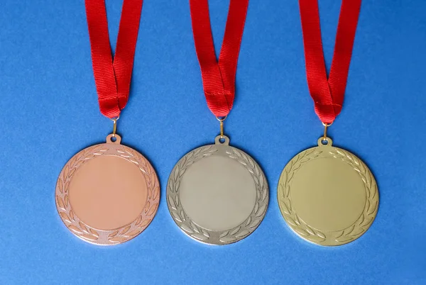 Gold, silver and bronze medals on blue background, flat lay. Space for design