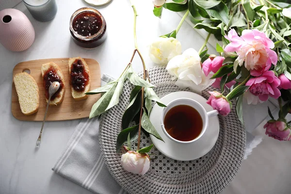 Beautiful peonies and breakfast on marble table, flat lay