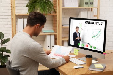 Genç adam evde online çalışmak için bilgisayar kullanıyor.
