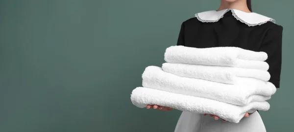 Junges Zimmermädchen Hält Stapel Sauberer Handtücher Auf Farbigem Hintergrund Nahaufnahme — Stockfoto