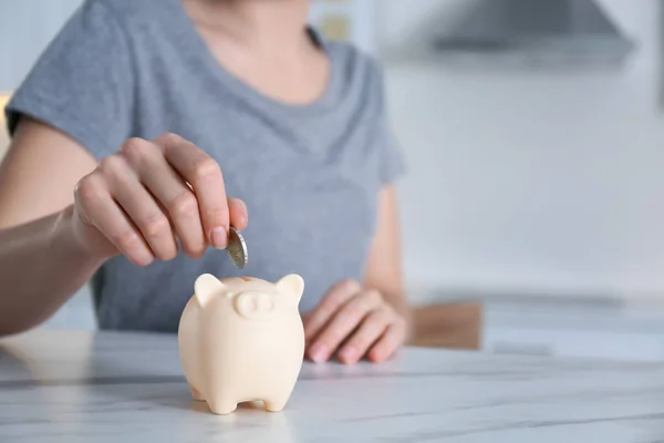 Woman Putting Money Piggy Bank Marble Table Indoors Closeup — Stock Photo, Image