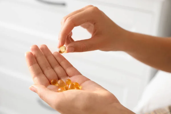 African-American woman with vitamin capsules at home, closeup