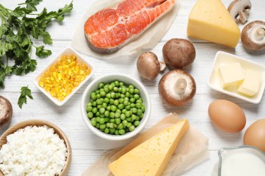 Beyaz ahşap masa üzerinde D vitamini açısından zengin ürünlerin olduğu düz bir kompozisyon.