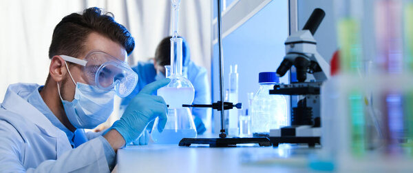 Young scientist doing research and analysis in chemical laboratory. Banner design  