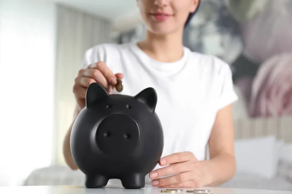 Mulher Colocando Dinheiro Banco Porquinho Mesa Branca Dentro Casa Close — Fotografia de Stock