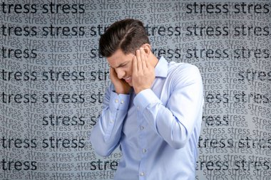 Depresyondan muzdarip genç adam ve gri arka planda STRESS kelimeleri