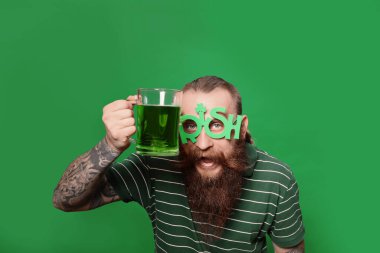 Parti gözlüklü, yeşil biralı sakallı adam. Aziz Patrick Günü kutlaması