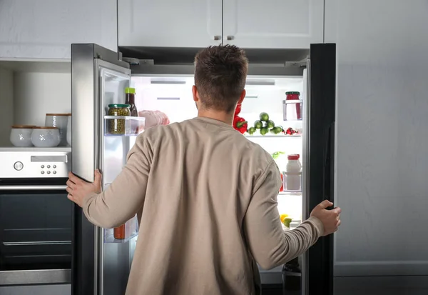 Hombre Joven Abriendo Refrigerador Interior Vista Trasera — Foto de Stock
