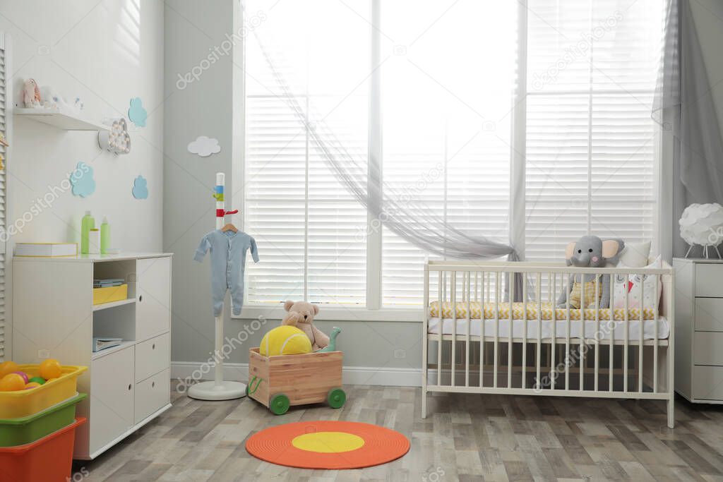 Stylish baby room interior with crib and toys