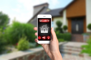 Evinin yakınındaki akıllı telefondan modern CCTV kameralarını izleyen bir kadın. Ev güvenlik sistemi