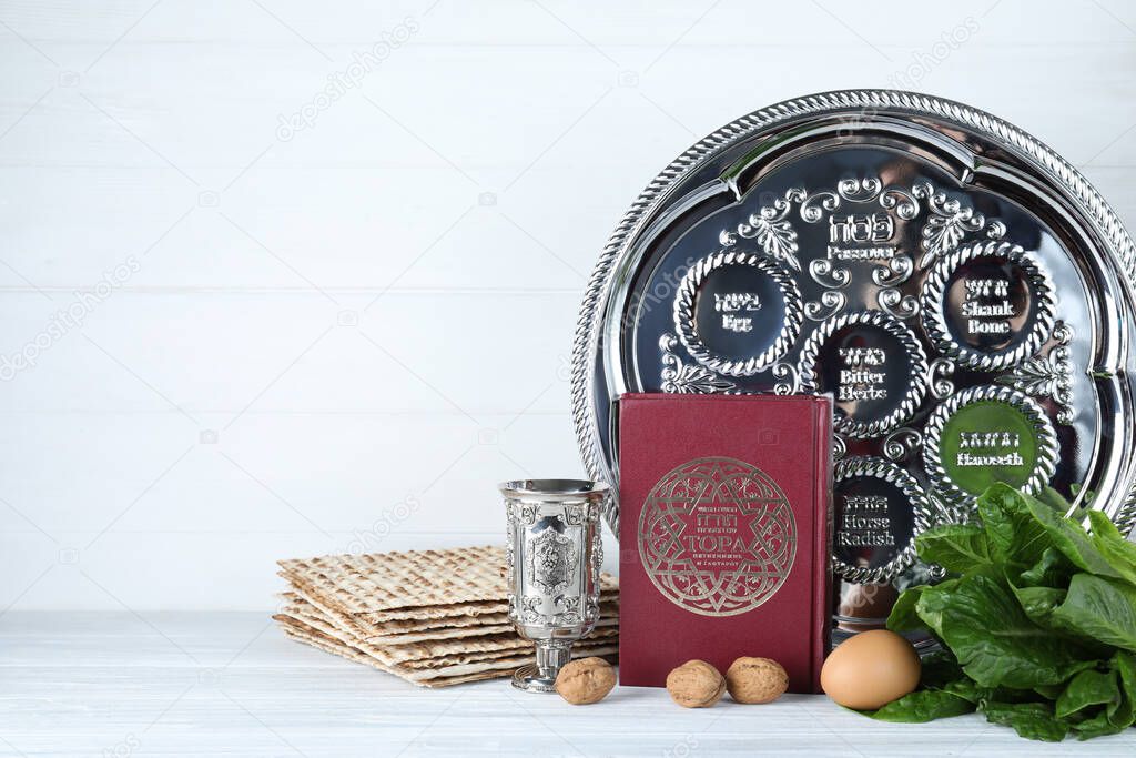 Symbolic Pesach (Passover Seder) items on white wooden table. Space for text