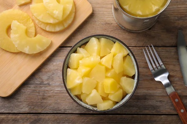 Flat lay composition with canned pineapple on wooden table