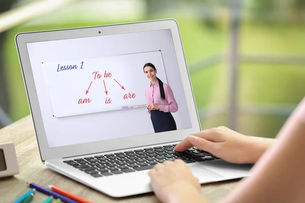 Woman using laptop for online English learning with teacher indoors, closeup