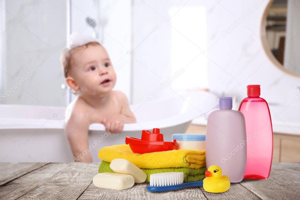 Baby cosmetic products, toys and towels on table in bathroom