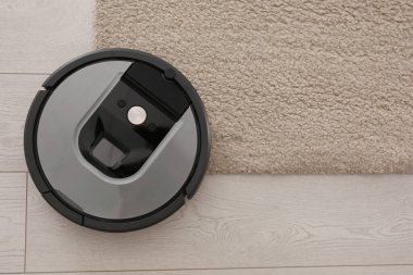 Bej halıda modern robotik elektrikli süpürge, üst manzara. Metin için boşluk
