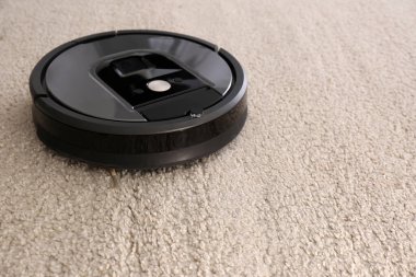 Bej halıda modern robot elektrikli süpürge. Metin için boşluk
