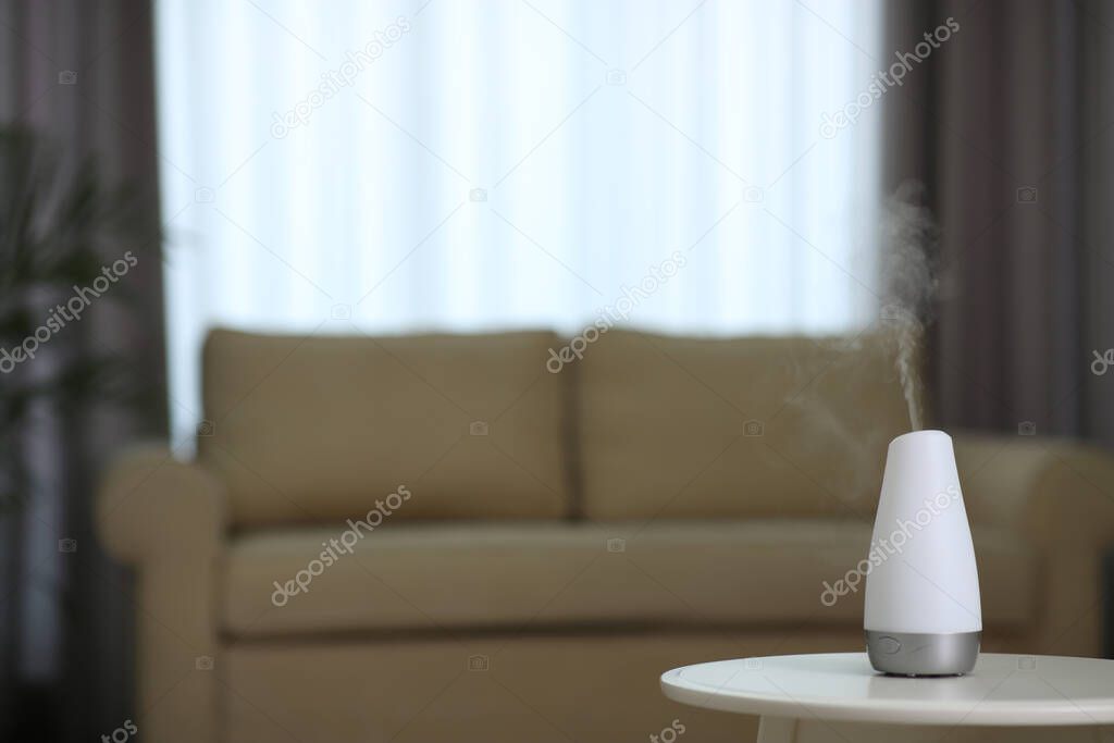 Aroma oil diffuser on table indoors. Space for text