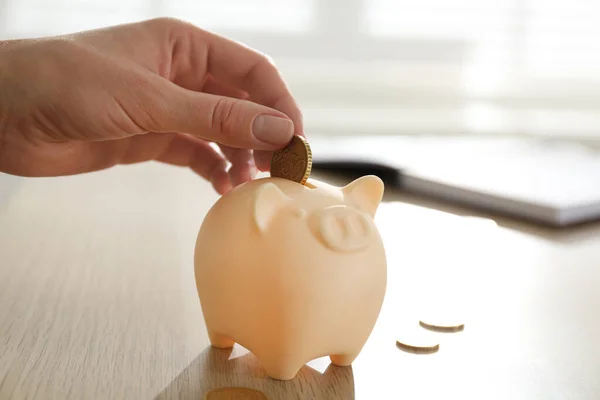 Woman Putting Money Piggy Bank Wooden Table Indoors Closeup — Stock Photo, Image