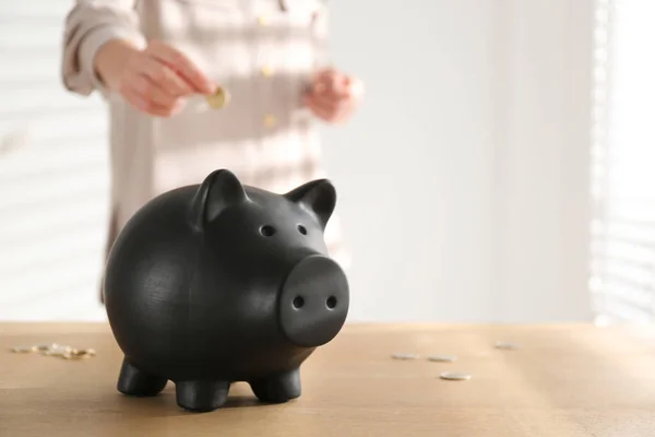 Woman Putting Money Piggy Bank Wooden Table Indoors Closeup Space — Stock Photo, Image