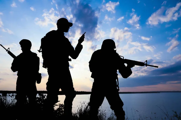 Katonák Sziluettjei Rohamfegyverekkel Hordozható Rádióadóval Szabadban Járőröznek Katonai Szolgálat — Stock Fotó