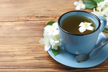 Bir fincan çay ve ahşap masada taze yasemin çiçekleri. Metin için boşluk