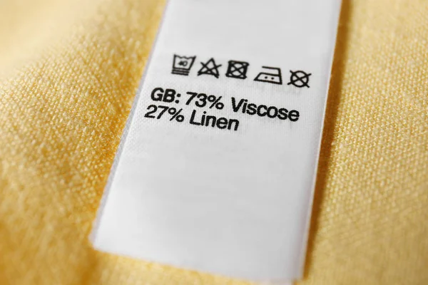 Etykieta Odzieżowa Symbolami Pielęgnacji Zawartością Materiału Żółtej Koszuli Widok Bliska — Zdjęcie stockowe