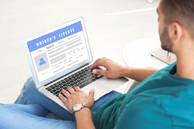 İnternet sitesinde dizüstü bilgisayarla sürücü belgesi dolduran adam