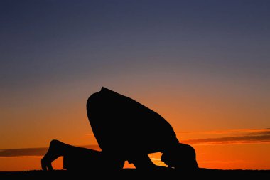 Gün batımında dua eden Müslüman bir adamın silueti. Kutsal Ramazan ayı