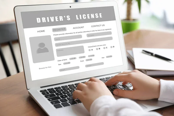 Woman filling in driver's license form online on website using laptop, closeup