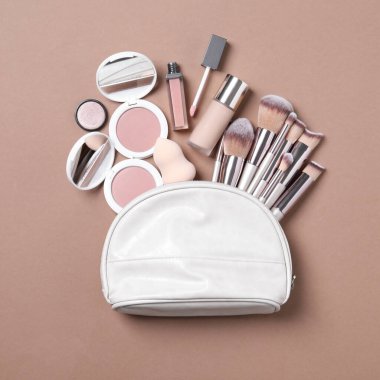Makyaj ürünleri ve kahverengi arka planda güzellik aksesuarları olan kozmetik çanta.