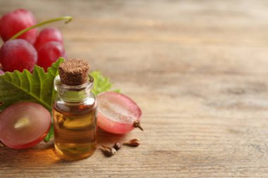 Bir şişe doğal üzüm tohumu yağı ahşap masada, yazı için yer var. Organik kozmetik