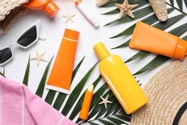 Beyaz ahşap zemin üzerinde güneş koruma ürünleri ve plaj aksesuarları, düz yatıyordu.