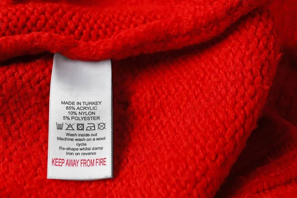 Kleding Label Met Zorg Symbolen Materiaal Inhoud Rode Trui Close — Stockfoto