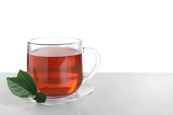 一杯芬芳的红茶和绿叶放在桌上 衬托着白色的背景 案文的篇幅 — 图库照片