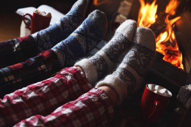 İçeride şöminenin yanında dinlenen pijamalı bir çift, yakın plan. Kış tatili