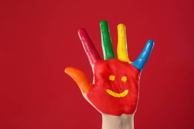 Avuç içine kırmızı arka planda gülümseyen çocuk, yakın plan