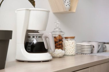Modern kahve makinesi ve fincanlar ahşap masa içinde.