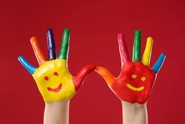 Kind Met Glimlachende Gezichten Getekend Handpalmen Tegen Rode Achtergrond Close — Stockfoto