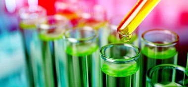 Bulanık arka planda test tüpüne sıvı damlatıyor, pankart tasarımı. Laboratuvar analizi